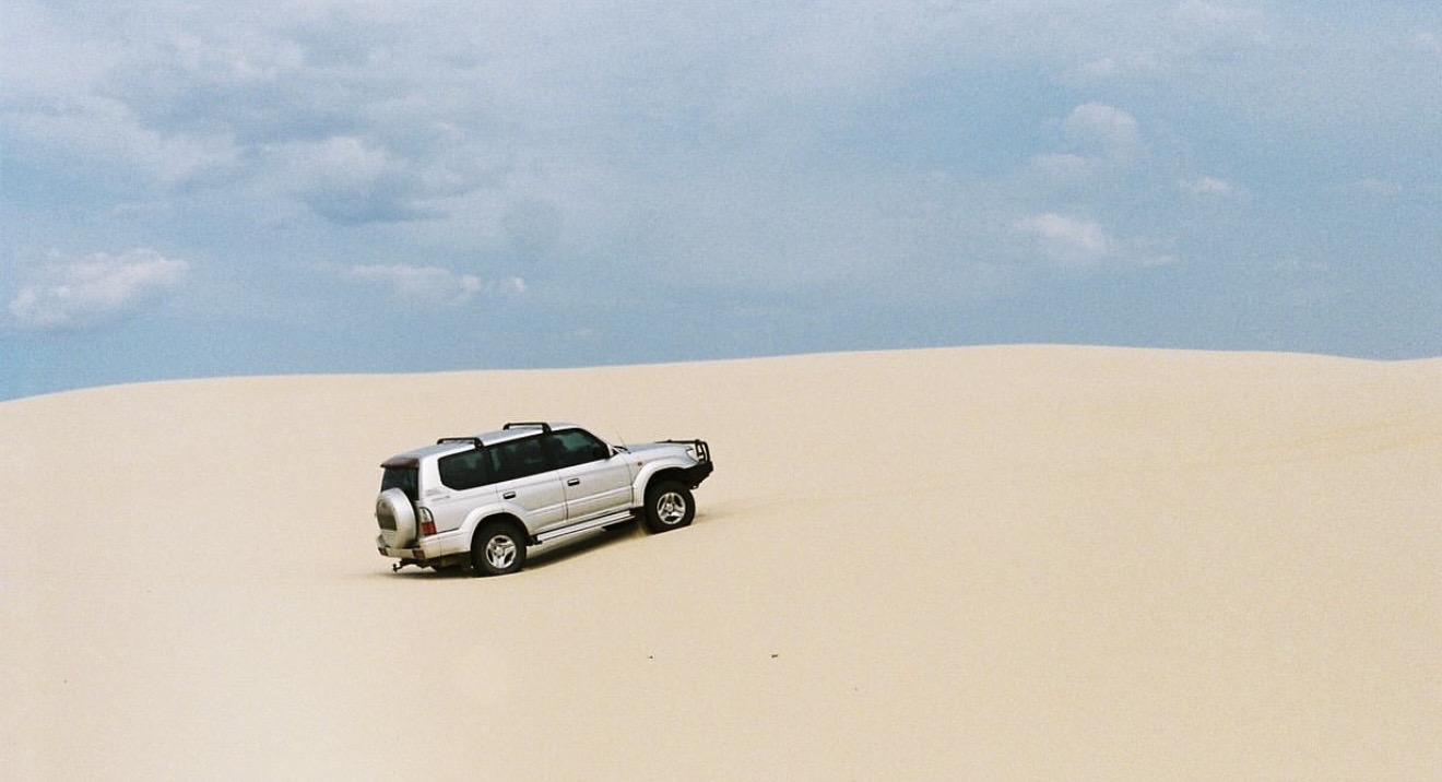 Toyota Prado cresting a sand dune